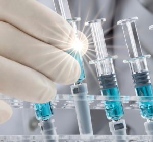 Closed up image of a doctor holding a prefilled syringe in a line up of similar syringes