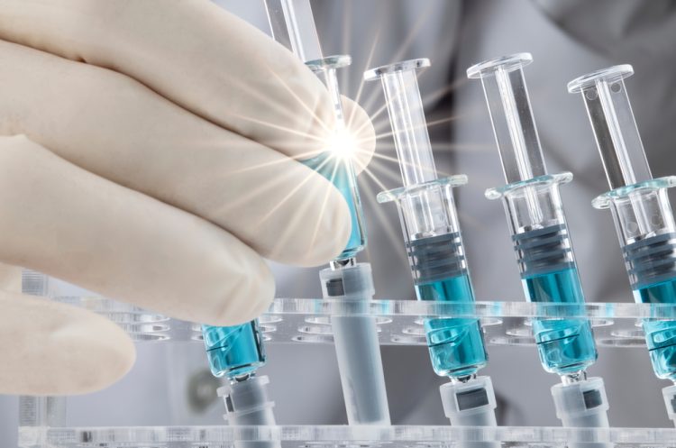 Closed up image of a doctor holding a prefilled syringe in a line up of similar syringes