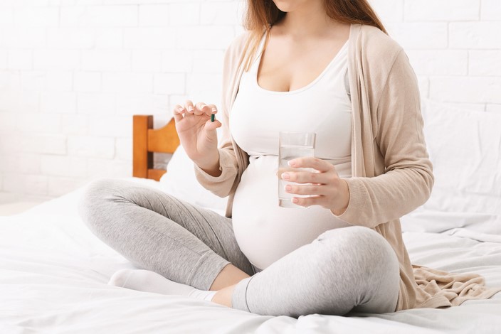 pregnant woman taking a tablet