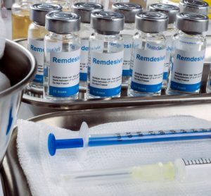 vials of remdesivir lined up next to a syringe and a bowl of cotton pads