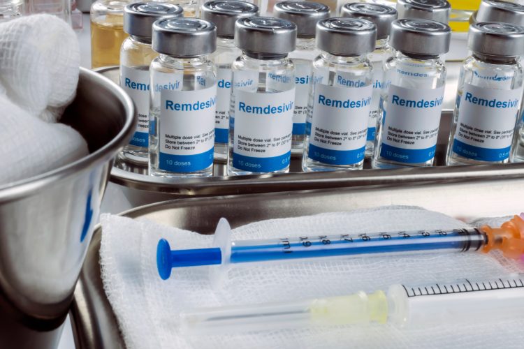 vials of remdesivir lined up next to a syringe and a bowl of cotton pads