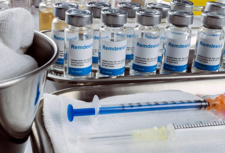 vials of remdesivir lined up next to a syringe and a bowl of cotton pads