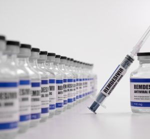 vials lined up labelled 'remdesivir' with one pulled out with a syringe balanced on it labelled the same