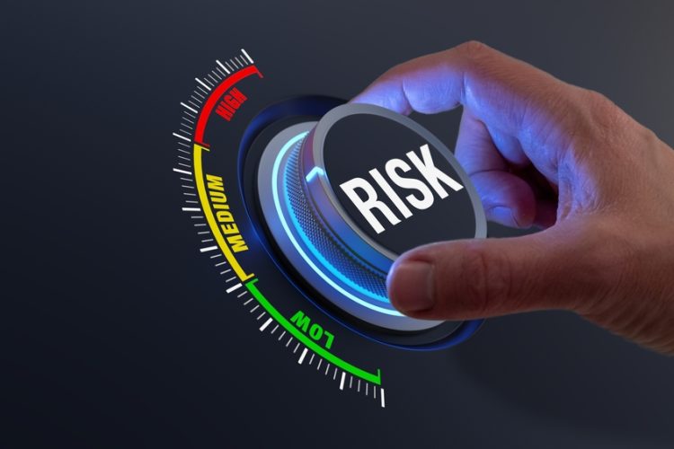concept of risk mitigation - hand turning a dial labelled risk from high to low
