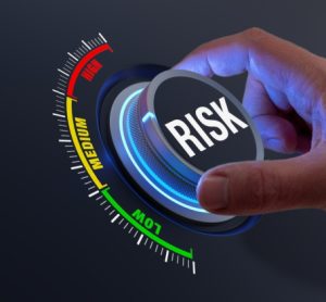 concept of risk mitigation - hand turning a dial labelled risk from high to low