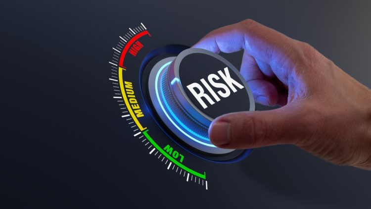 concept of risk mitigation - hand turning a dial labelled risk from high to low