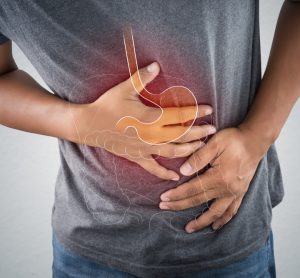 Man clenching stomach with faded illustration of stomach