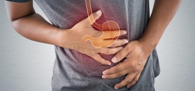 Man clenching stomach with faded illustration of stomach