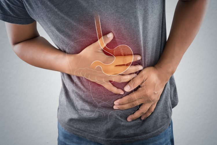 Man clenching stomach with faded illustration of stomach