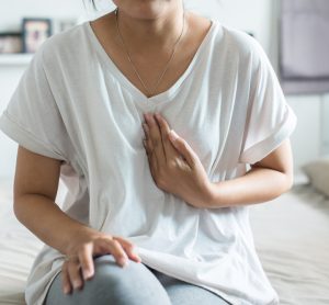 Woman in pain touching chest where oesophagus is