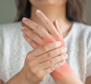 Woman holding sore hand, indicating juvenile arthritis
