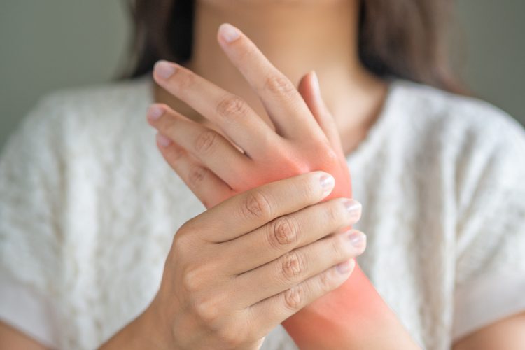 Woman holding sore hand, indicating juvenile arthritis