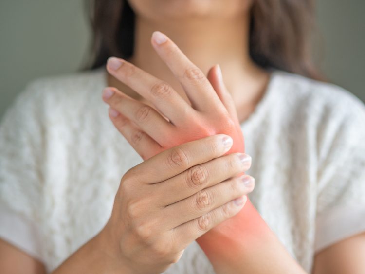 Woman holding sore hand, indicating juvenile arthritis