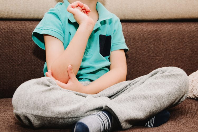 Boy with arthritis holding elbow