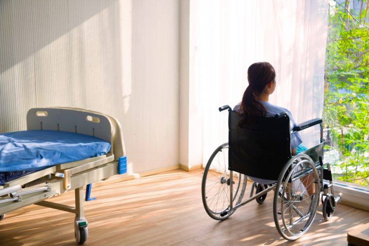 Woman sitting in wheelchair in hospital room