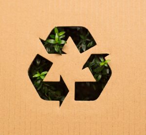 Recyclable logo (three green arrows) on a brown background - idea of sustainability/environmentally friendly practices