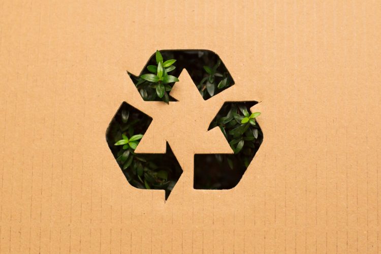 Recyclable logo (three green arrows) on a brown background - idea of sustainability/environmentally friendly practices
