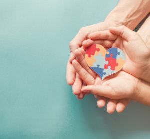 Hands holding heart made from jigsaw pieces, symbolising autism awareness