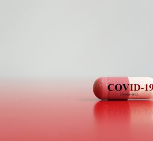 Red and white pill with COVID-19 written on it