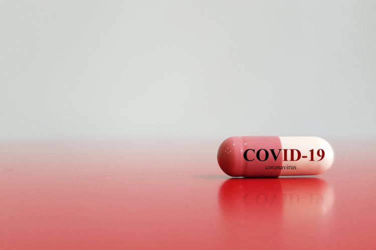 Red and white pill with COVID-19 written on it