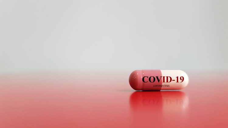 Red and white pill with COVID-19 written on it