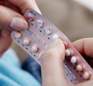 Close up of hands holding contraceptive pills