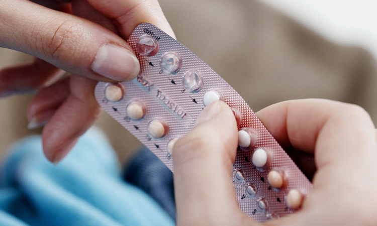 Close up of hands holding contraceptive pills