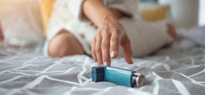 Woman reaching for asthma pump on bed