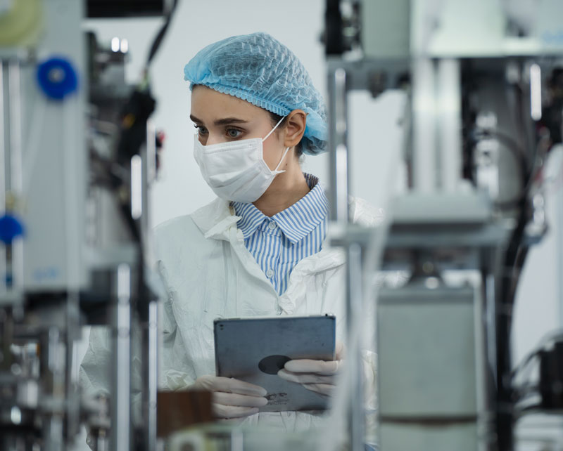 Woman in protective lab clothing illustrating continuous manufacturing