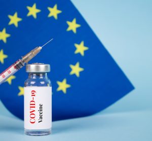 COVID-19 vaccine in front of EU flag