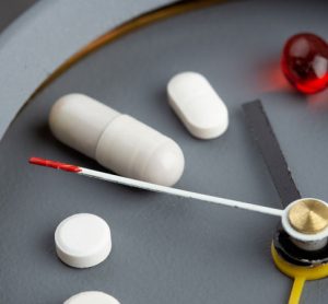 Pills on clock face illustrating delivery method for biologics
