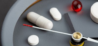 Pills on clock face illustrating delivery method for biologics