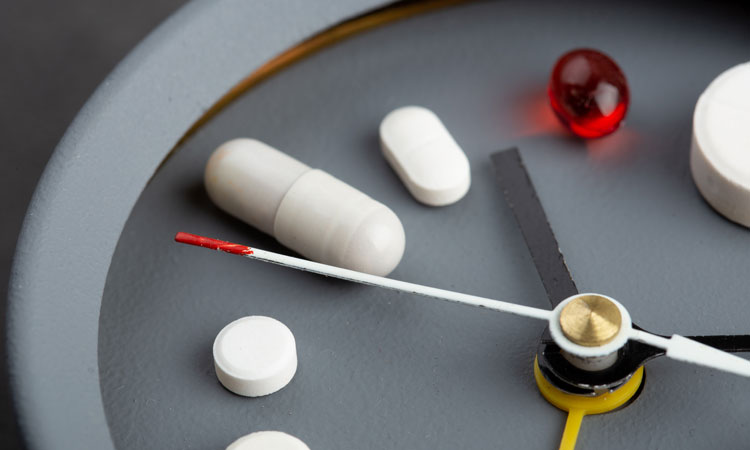 Pills on clock face illustrating delivery method for biologics