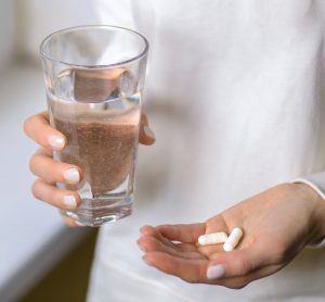 Woman holding pills and glass of water