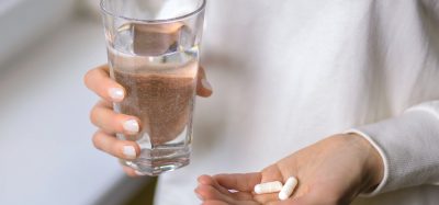 Woman holding pills and glass of water