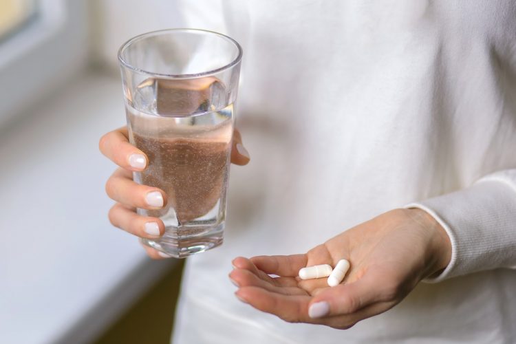 Woman holding pills and glass of water