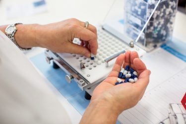 Hand placing pills in grid