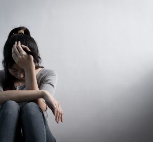 Woman with depression sitting down with head in hand