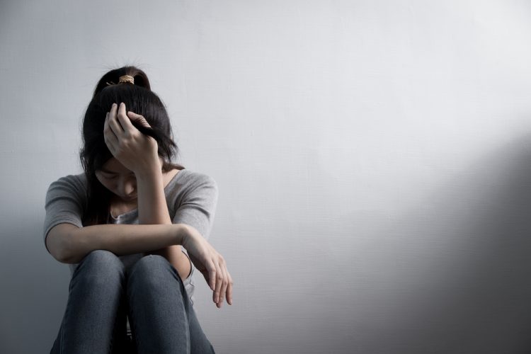 Woman with depression sitting down with head in hand