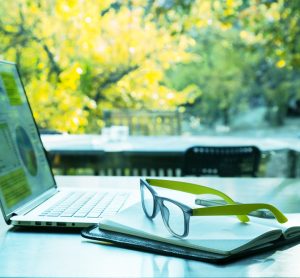 Laptop on table in front of background of trees