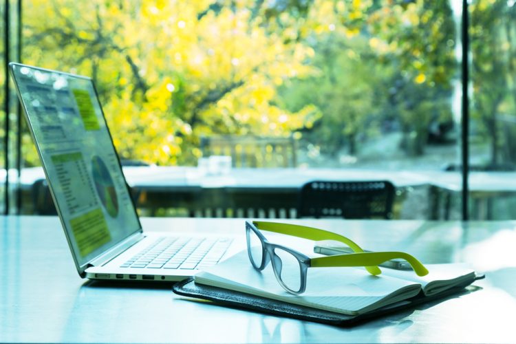 Laptop on table in front of background of trees