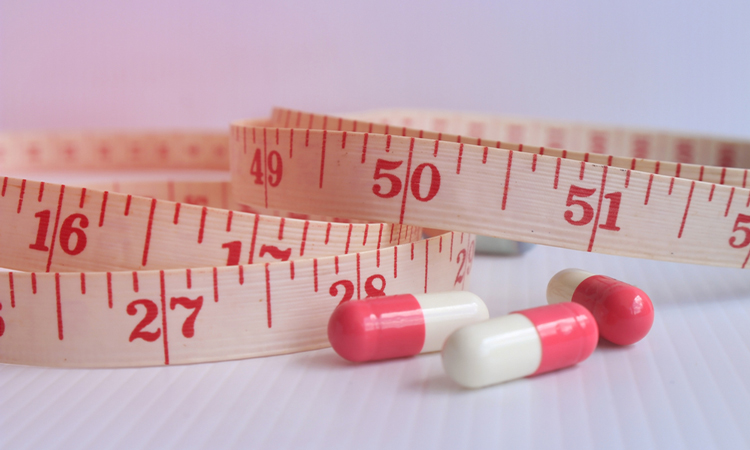 Pills next to tape measure