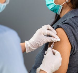 Close up of doctor holding a syringe ready to vaccinate a patient in their upper arm