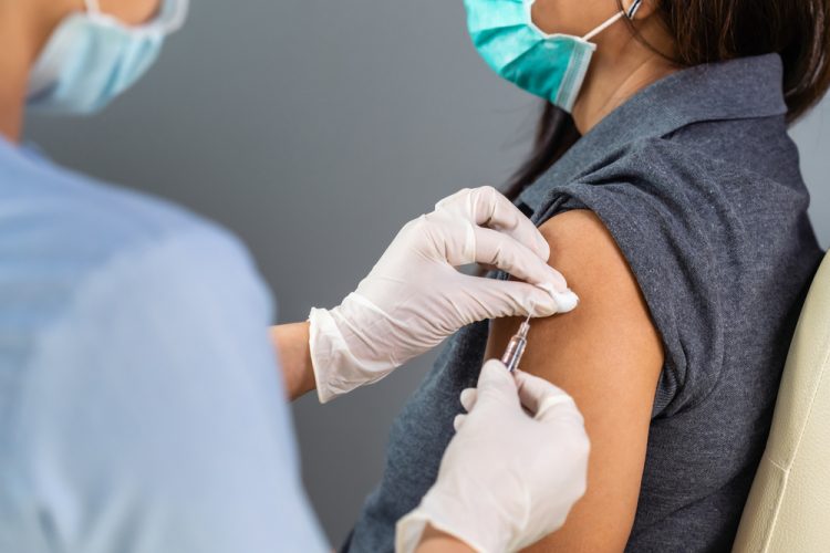 Close up of doctor holding a syringe ready to vaccinate a patient in their upper arm