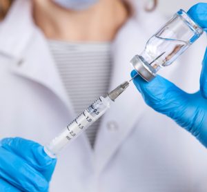 doctor drawing a vaccine dose into a syringe from an unlabelled vial