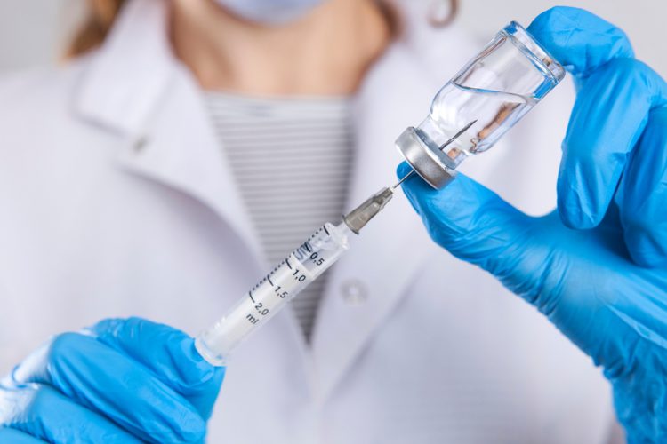 doctor drawing a vaccine dose into a syringe from an unlabelled vial