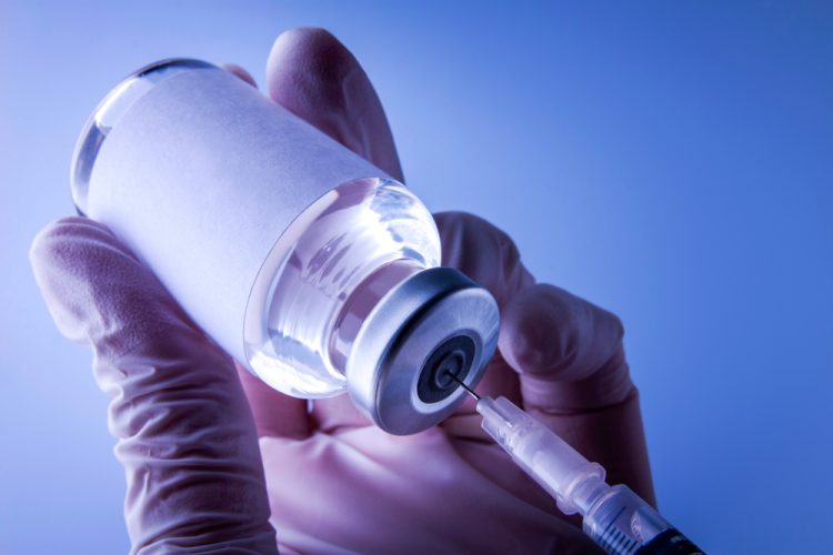 close up of a syringe drawing a vaccine dose from a glass vial