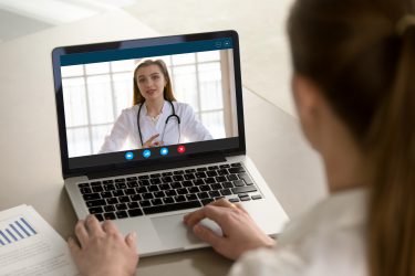woman looking at a doctor on her laptop screen during a virtual appointment